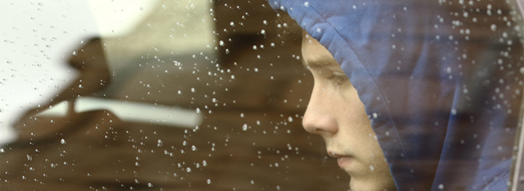 Young man in car with hood up