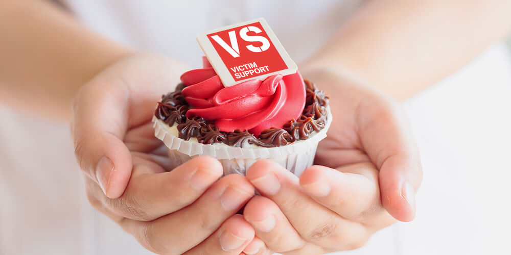 Hands holding a cupcake with a VS logo on top