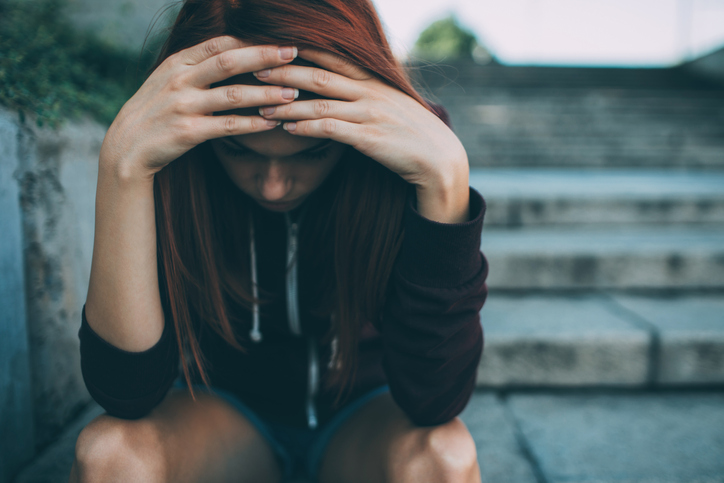 Young girl holds head in her hands.